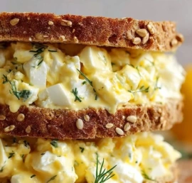 Delicious cottage cheese egg salad sandwich on a plate with fresh herbs.