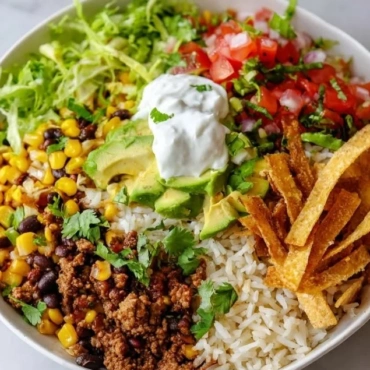 A colorful homemade burrito bowl filled with fresh ingredients and toppings.