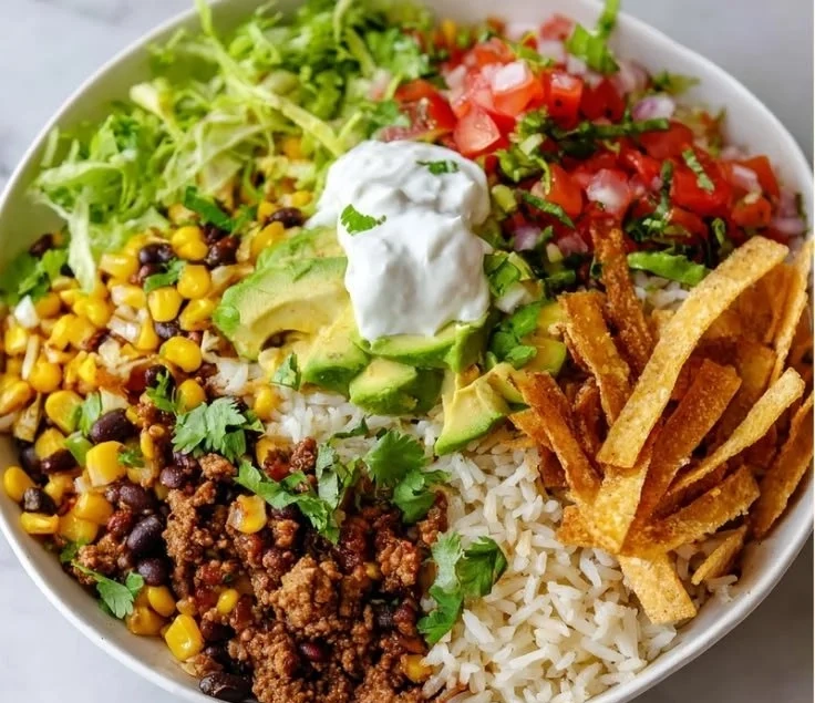A colorful homemade burrito bowl filled with fresh ingredients and toppings.