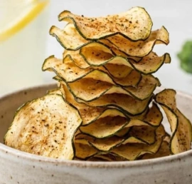 Bowl of crispy oven-baked zucchini chips ready to be served as a healthy snack.