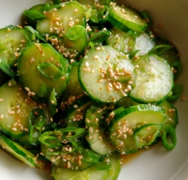Sesame cucumber salad with thin cucumber slices green onions and sesame seeds in a bowl