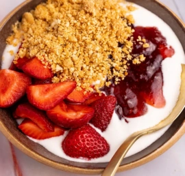 High-protein Strawberry Cheesecake Yogurt Bowl with fresh strawberries and graham crackers.