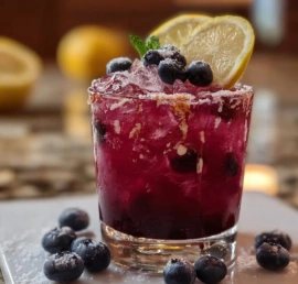 Glass of Blueberry Lemon Fizz cocktail with fresh blueberries and lemon slices