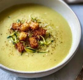 Bowl of creamy zucchini soup garnished with fresh herbs