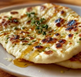 Freshly baked garlic pita bread served on a wooden board.