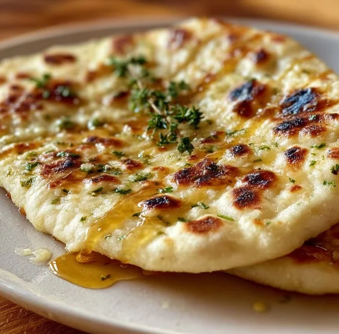 Freshly baked garlic pita bread served on a wooden board.