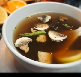 Bowl of Japanese clear soup with vegetables and herbs