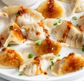 Delicious homemade potstickers served with dipping sauce on a plate.