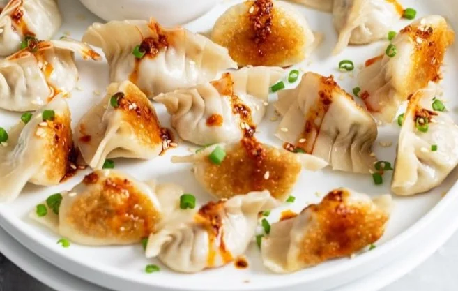 Delicious homemade potstickers served with dipping sauce on a plate.