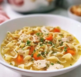 Bowl of homemade turkey noodle soup with vegetables and herbs