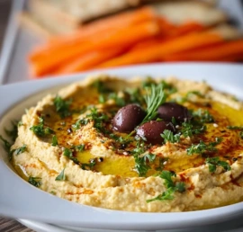 Delicious olive hummus served with pita chips and fresh vegetables