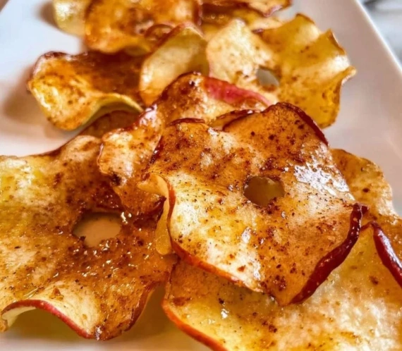 Easy air fried apple chips on a plate with a sprinkle of cinnamon.